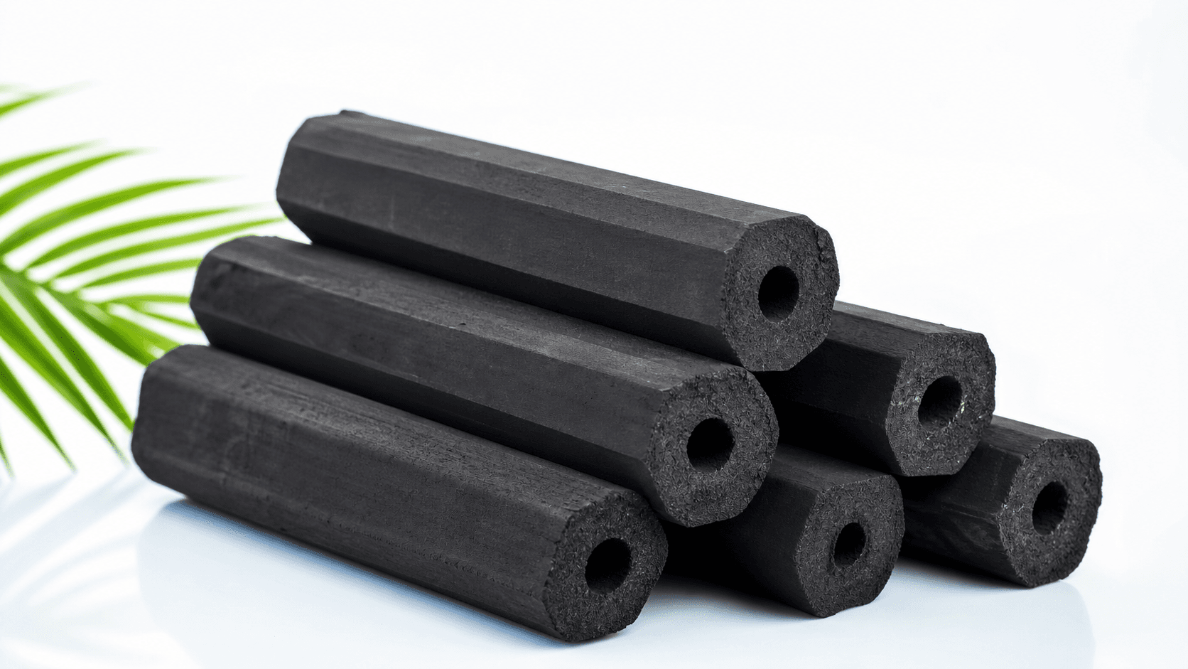 Long black hexagonal coconut-shell briquettes with a central bore.